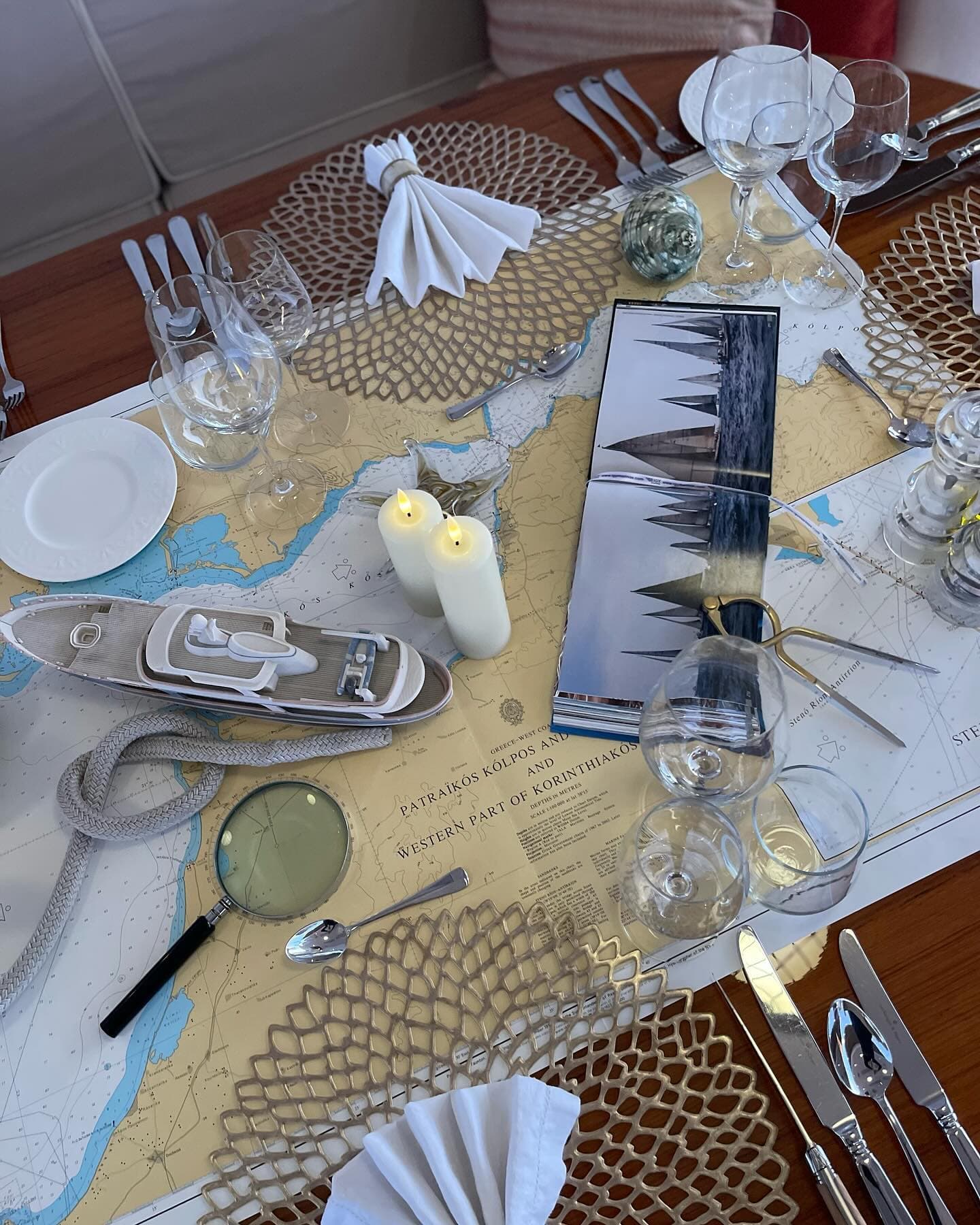 Place setting laid over an Admiralty chart of the Gulf of Corinth