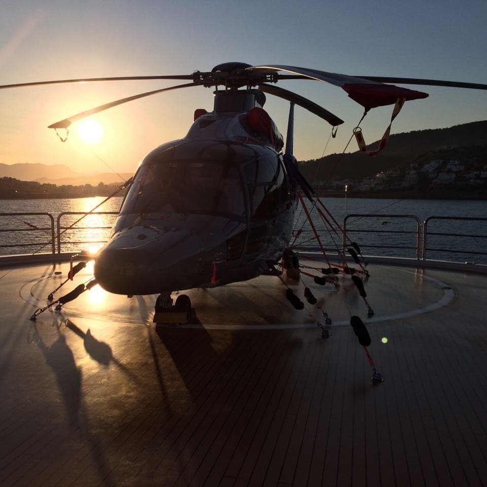 Helicopter lashed to the yacht's helipad at sunset