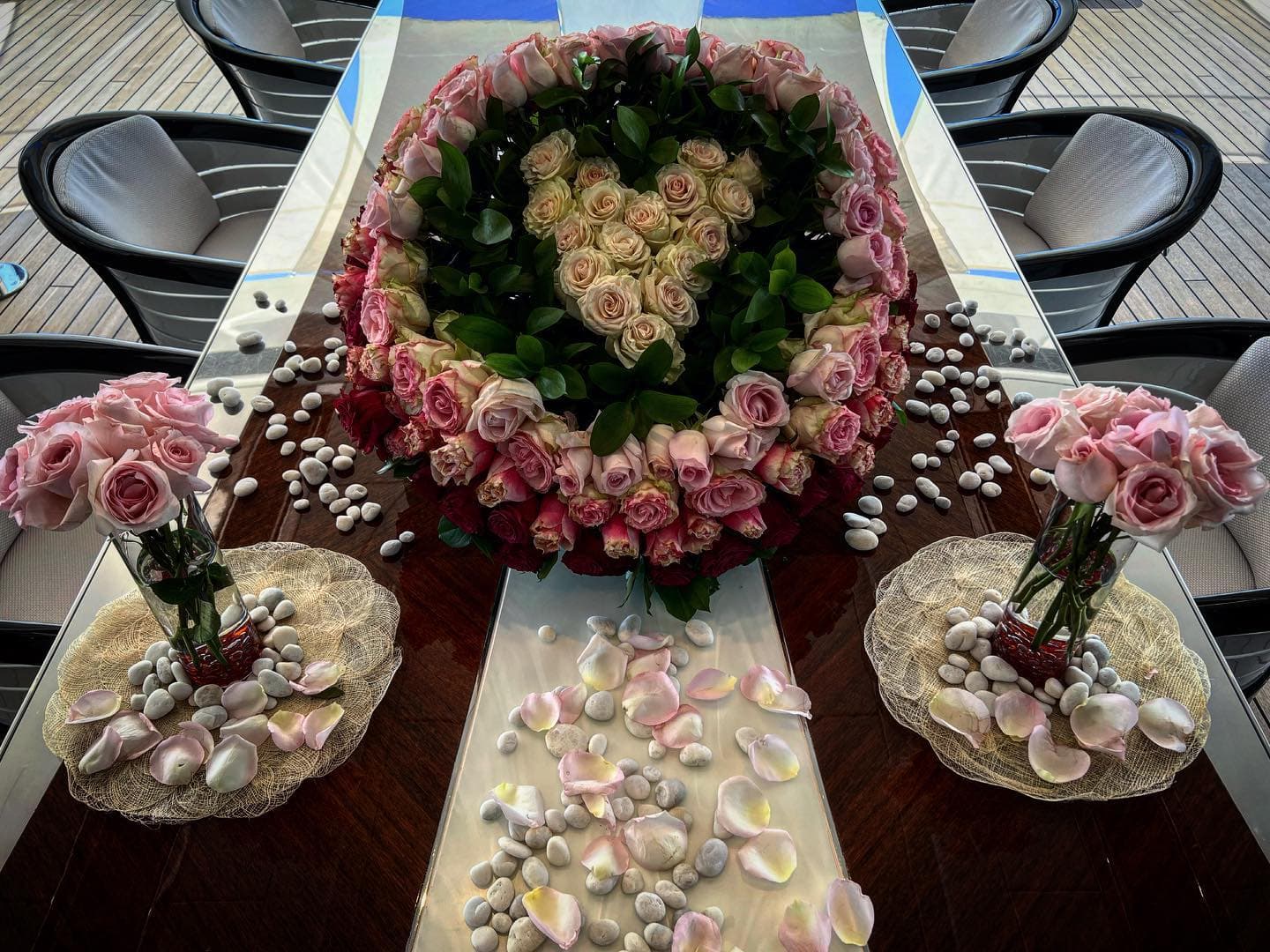 Rose centrepiece and petal detail on a dining table on deck