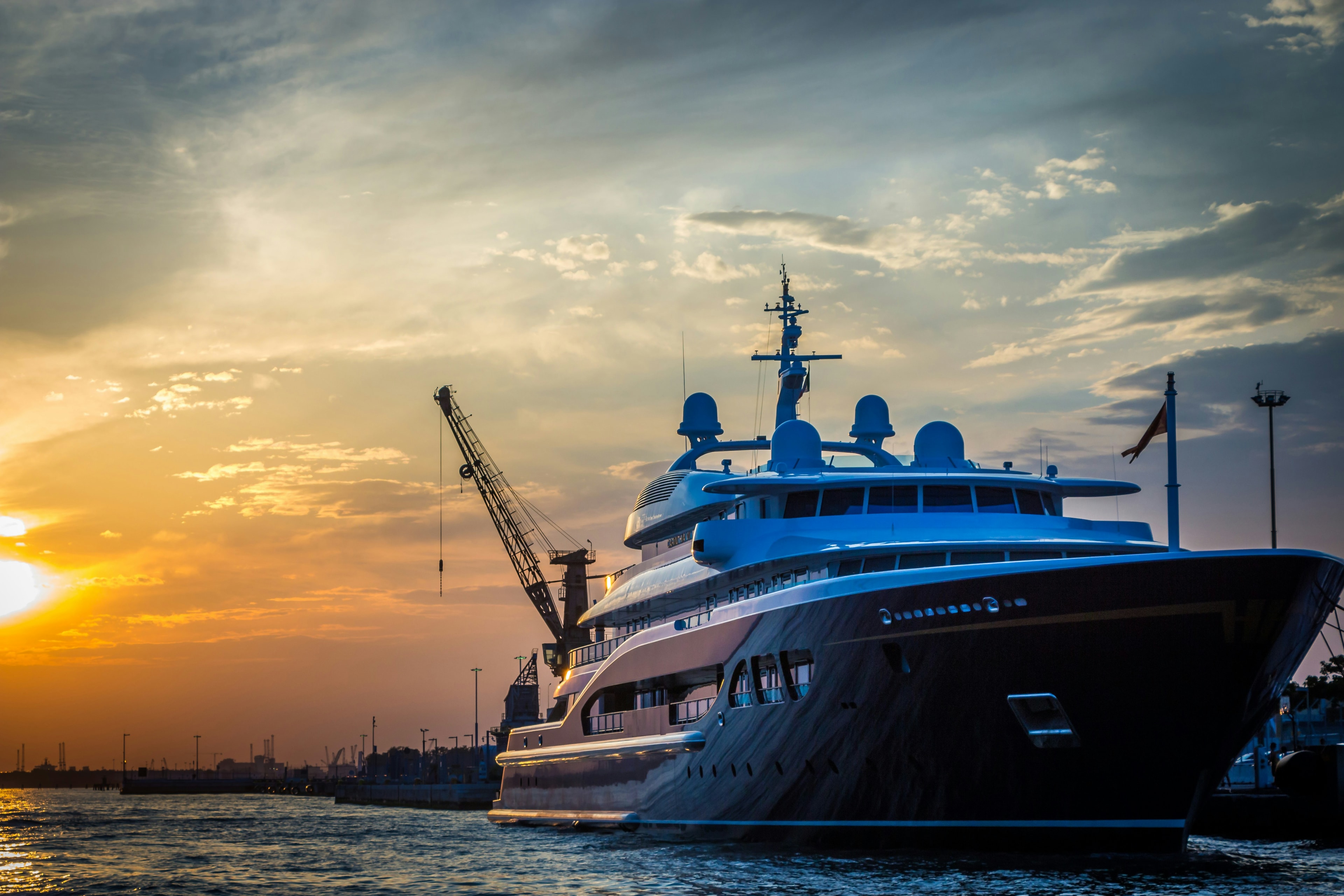 A superyacht berthed at a quay at sunset