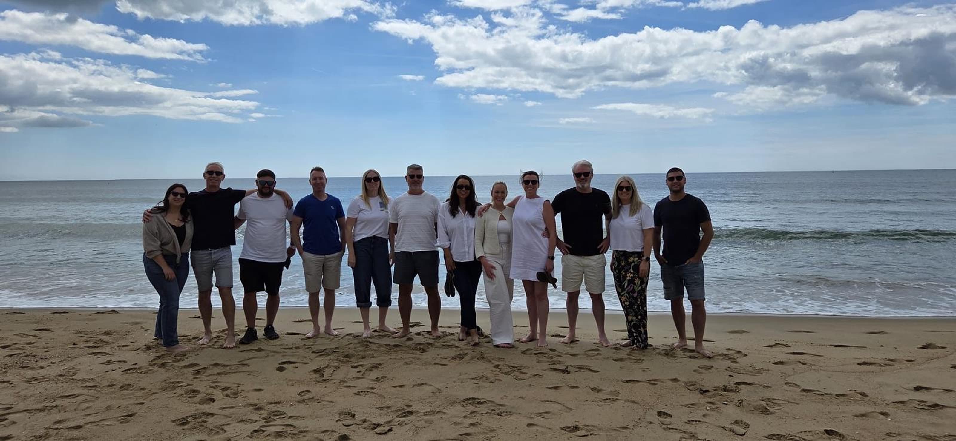 The Quay Group team standing together on Bournemouth beach with the sea behind them