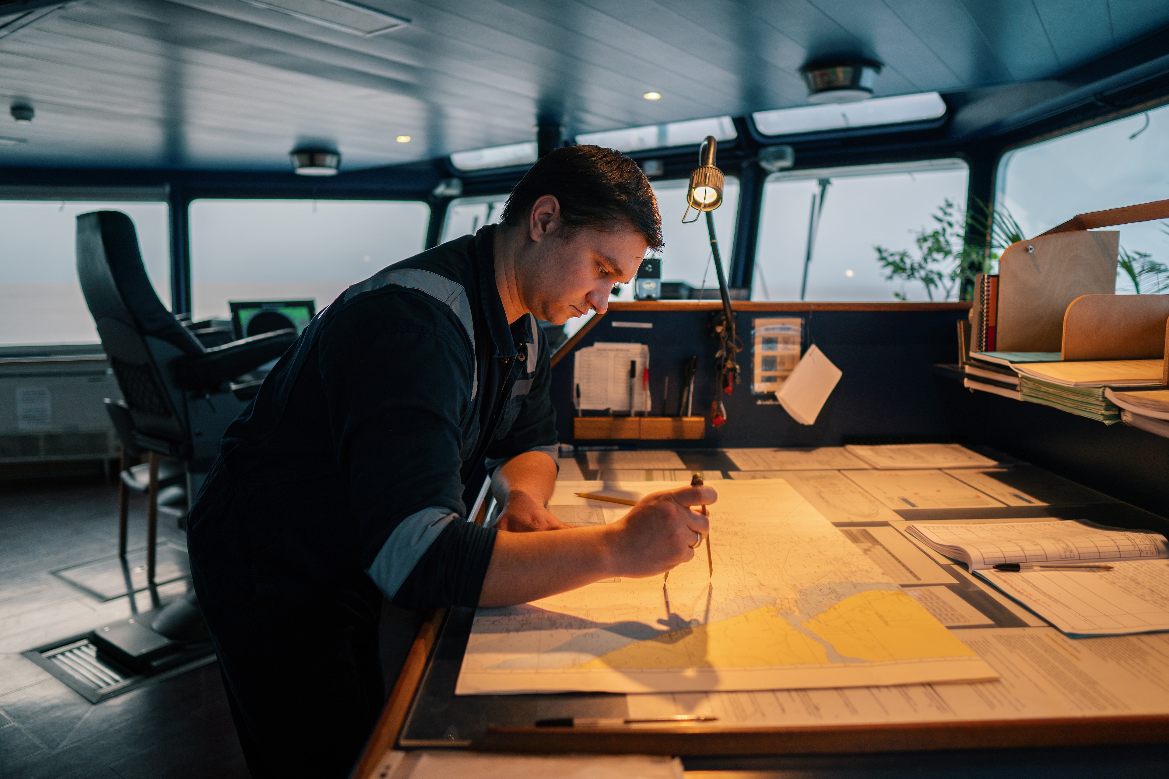 Submit a brief for your next shore-side hire. A navigator plotting a course on a chart on a vessel bridge