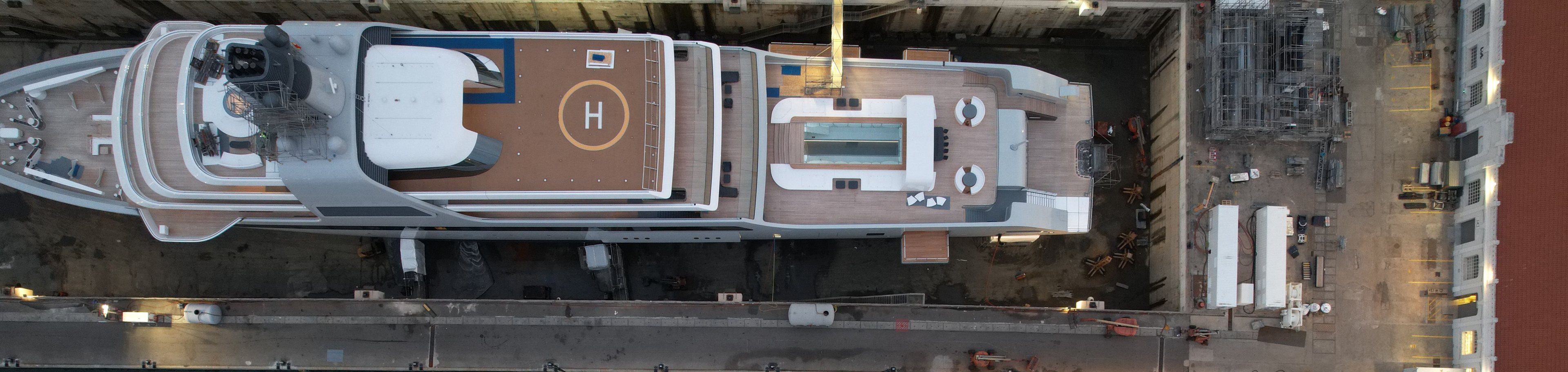 Speak with the maritime team. A superyacht in dry dock beside a quay, seen from directly overhead